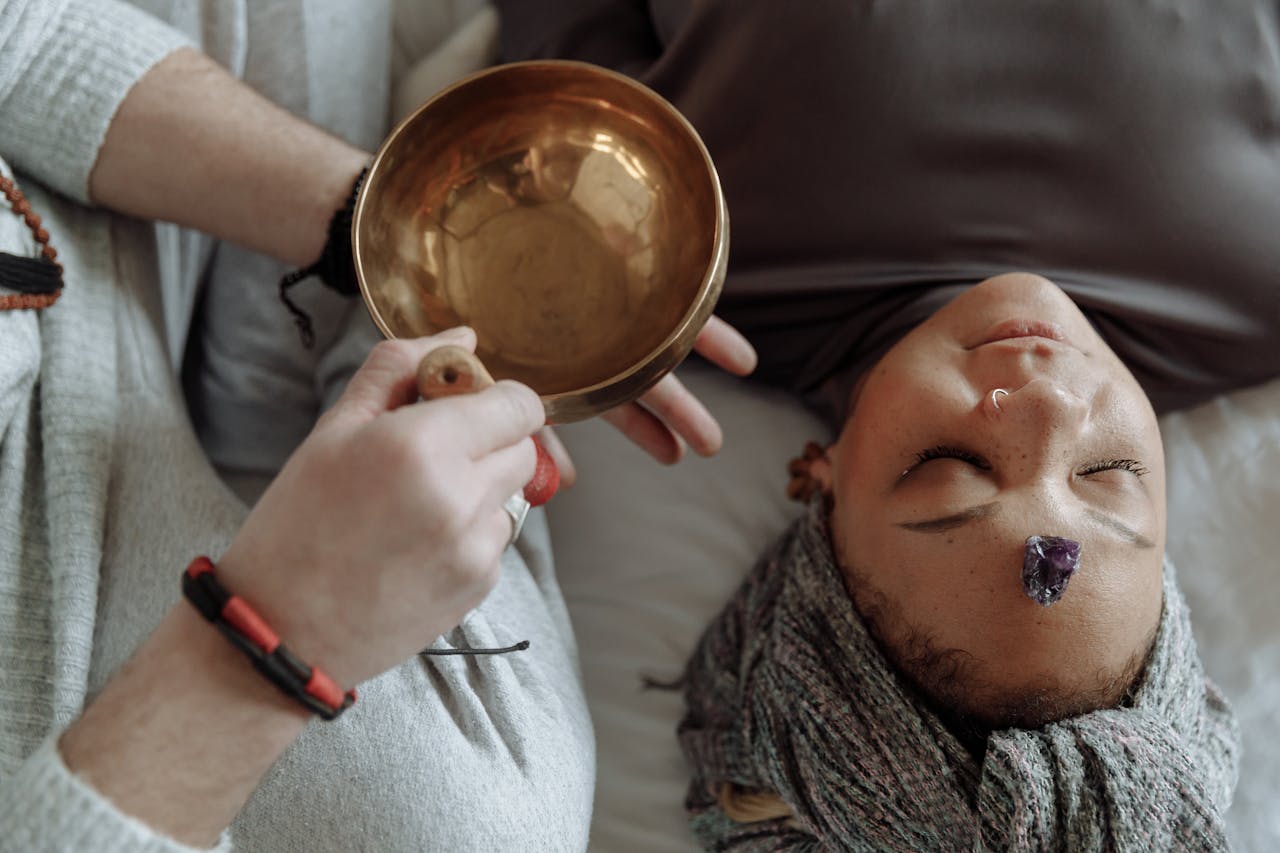 Woman receiving healing therapy with a Tibetan singing bowl placed during meditation.